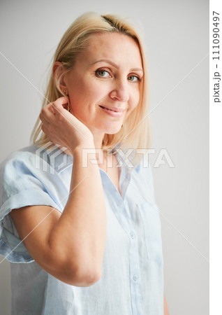 Close up portrait of smiling woman. Gentle female smiling to camera. Beautiful woman fixing her hair. 111090497