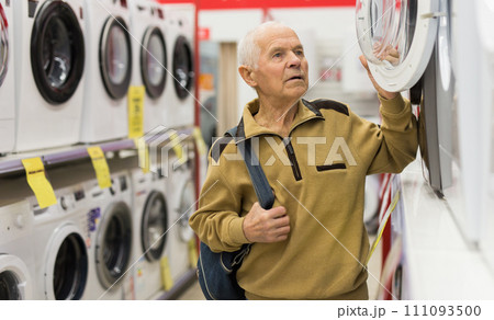 Senor man pensioner buying washing machine in showroom of electrical appliance store 111093500
