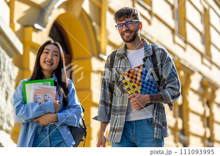 Multicultural guy and girl walking together near the university. 111093995