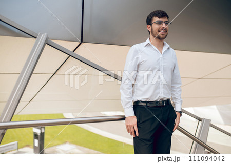 Contented young man looking confident and smiling Contented young man looking confident and smiling 111094042