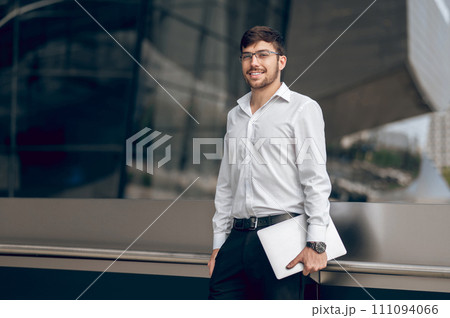 Young male manager with a laptop looking contented 111094066