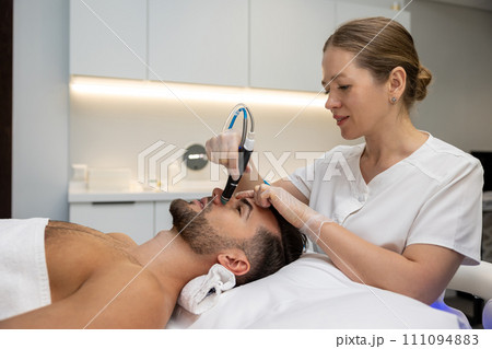 Beautician working with a customer and using current therapy Beautician working with a customer and using current therapy 111094883