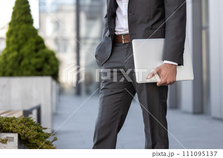 Close up of elegant man with a laptop in hands walking Close up of elegant man with a laptop in hands walking 111095137