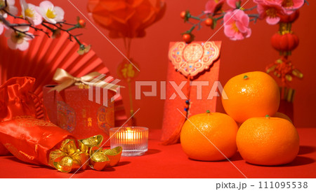 Chinese Lunar New Year red background. ancient Chinese gold bar in silk bag, gift box, paper fan, red envelope, ang pow, orange, plum blossom branch, candle and red paper lantern hanging for decorate 111095538