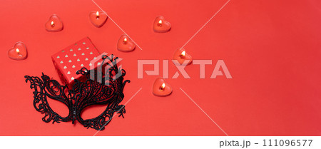 Banner Valentine's day black lace mask andgiftbox with gold hearts on red background with rose petals 111096577