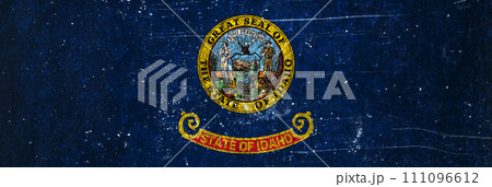 Close-up of the grunge Idaho state flag. Dirty Idaho state flag on a metal surface. 111096612