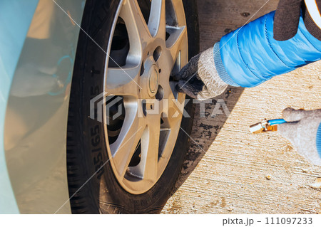 Hand holds the pressure gauge and fills the car tires with air. Car maintenance. 111097233