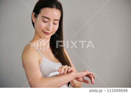 電気シェーバーで腕毛を剃る30代女性 111098696