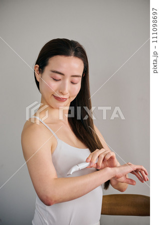 電気シェーバーで腕毛を剃る30代女性 111098697