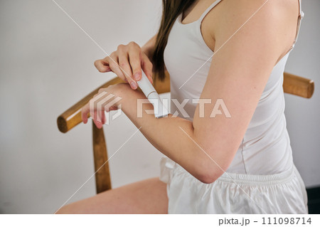 電気シェーバーで腕毛を剃る30代女性 111098714