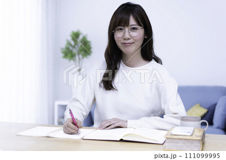 明るいリビングで勉強する眼鏡の女性 111099995