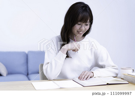 明るいリビングで勉強する眼鏡の女性 111099997