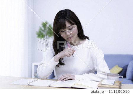 明るいリビングで勉強する眼鏡の女性 明るいリビングで勉強する眼鏡の女性 111100010