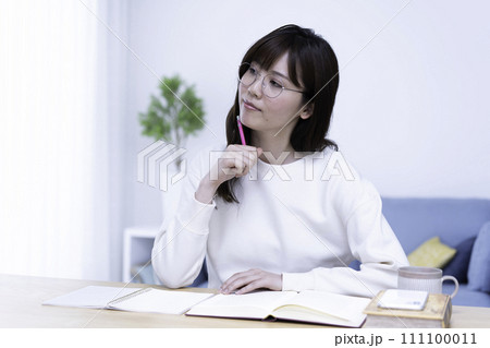 明るいリビングで勉強する眼鏡の女性 明るいリビングで勉強する眼鏡の女性 111100011