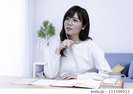 明るいリビングで勉強する眼鏡の女性 明るいリビングで勉強する眼鏡の女性 111100012
