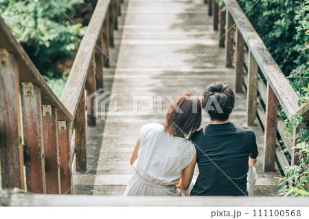 橋の階段で肩にもたれるカップルの後ろ姿 111100568