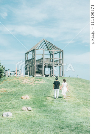 公園で手をつなぎ丘を登っていく男女 公園で手をつなぎ丘を登っていく男女 111100571