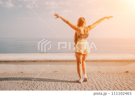 Woman summer dance. Silhouette of a happy woman who dances, spins and raises her hands to the sky. A playful young woman enjoys her happy moment dancing in the rays of the golden sun. 111102463