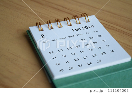 Close up side view of February 2024 calendar on wooden desk. Calendar concept Close up side view of February 2024 calendar on wooden desk. Calendar concept 111104002