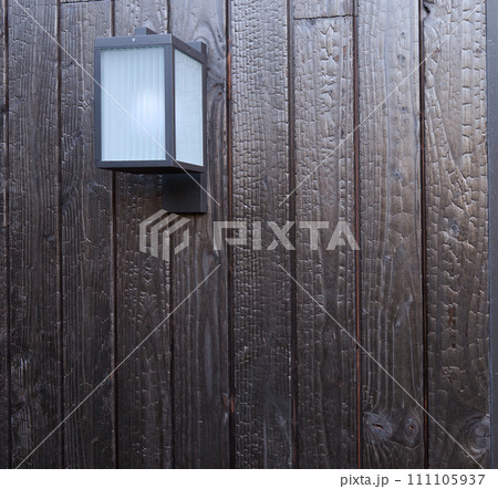 Modern external lamp on burned wood wall Modern external lamp on burned wood wall 111105937
