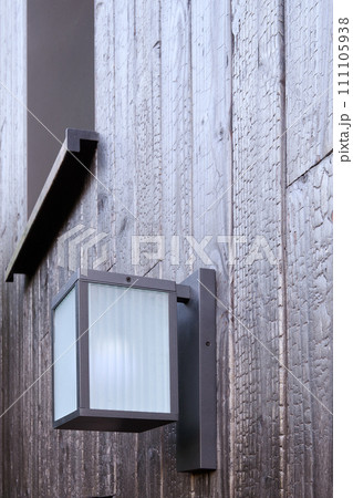 Modern external lamp on burned wood wall 111105938