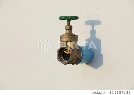 Water shut off valve installed on white wall with shadow. 111107235
