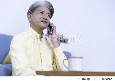 リビングでスマホ通話するミドルの男性 111107892