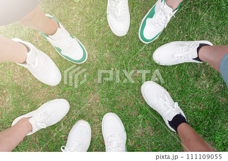 Friends putting their shoes together in a circle. Youth in white sneakers. 111109055