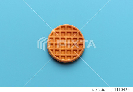Round waffle directly above view, isolated on a blue background Round waffle directly above view, isolated on a blue background 111110429