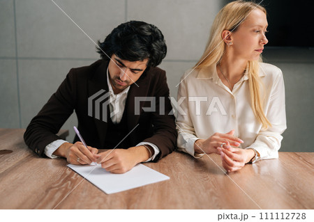 Portrait of sad spouses couple signing decree papers getting divorced in lawyers office at desk. Unhappy married family split break up end relationships giving permission to marriage dissolution. Portrait of sad spouses couple signing decree papers getting divorced in lawyers office at desk. Unhappy married family split break up end relationships giving permission to marriage dissolution. 111112728
