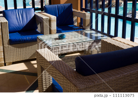 Balcony terrace with wicker chairs and a table with an ashtray for smoking in the fresh air while relaxing on a sunny day 111113075