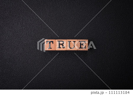 The inscription True made of wooden cubes on a plain background 111113184