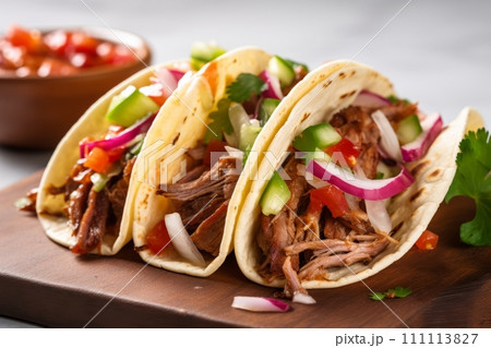 Mexican pork carnitas tacos with greens, tomato and veggies on the wooden board 111113827