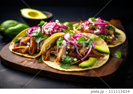 Three Mexican pork carnitas tacos with greens, avocado and onion on the wooden board Three Mexican pork carnitas tacos with greens, avocado and onion on the wooden board 111113834