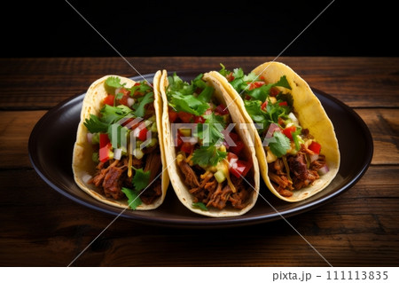 Juicy beef tacos topped with veggies side by side on the black plate on wooden table 111113835