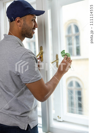 Bearded man washing dusty window in apartment. 111114555