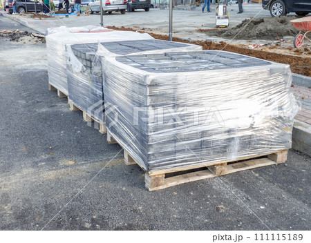 Pavement repair. Laying out paving stones. Paving stones in pallets in polyethylene. Pavement repair. Laying out paving stones. Paving stones in pallets in polyethylene. 111115189