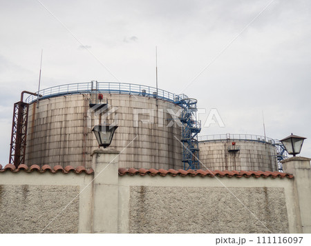 Large fuel tanks. Tanks and ladders of the tank farm. The gloomy atmosphere of an industrial area. 111116097