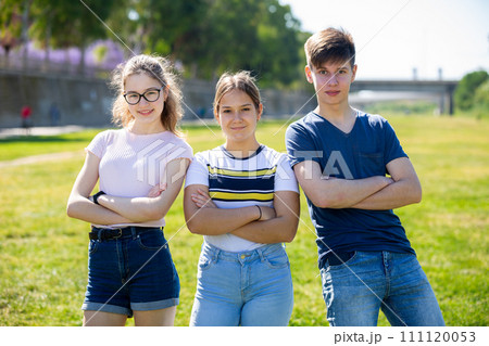 Cheerful teen friends with arms crossed on green lawn Cheerful teen friends with arms crossed on green lawn 111120053