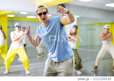 Emotional teen boy dancing with group of friends in dance studio. Hip hop generation 111120310