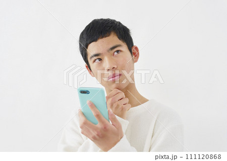 スマートフォンを持って考える男の子　白背景 111120868