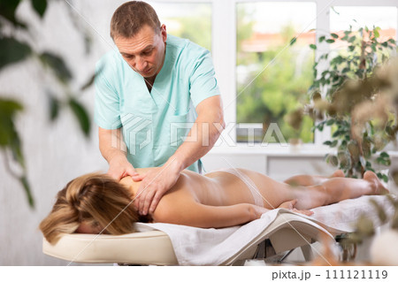 Woman enjoys back massage during spa treatments at cosmetology center Woman enjoys back massage during spa treatments at cosmetology center 111121119