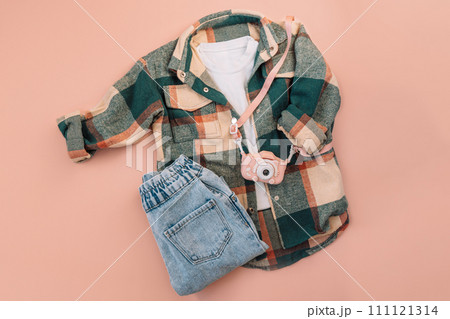 Children's checkered shirt and blue jeans with digital camera on pink background Children's checkered shirt and blue jeans with digital camera on pink background 111121314