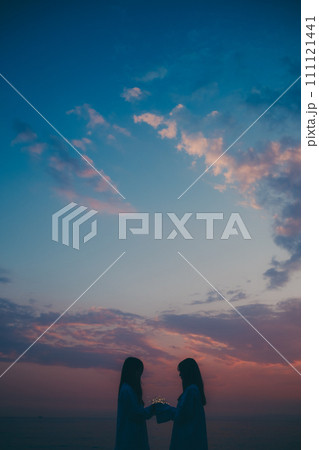 雲海に沈む夕日を眺める若い女性のシルエット 111121441