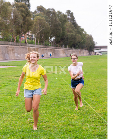 Laughing girlfriends are jogging together in park and having fun 111121647