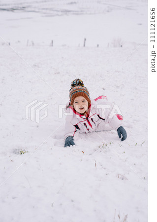Little smiling girl lying on her stomach in the snow Little smiling girl lying on her stomach in the snow 111121656