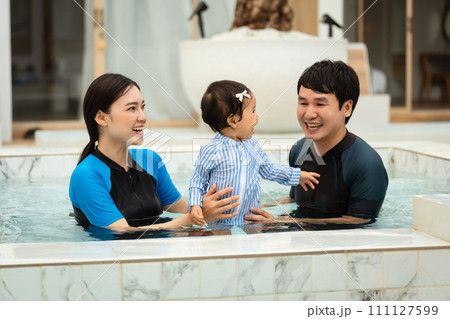 happy family. father and mother with small daughter in swimming pool. 111127599