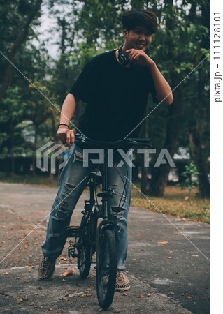 Young handsome bearded man taking a break while travelling the city with his bicycle using his digital tablet looking away thoughtfully 111128101