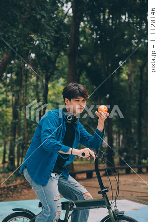 Young handsome bearded man taking a break while travelling the city with his bicycle using his digital tablet looking away thoughtfully 111128146
