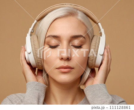 Close-up portrait of a young blonde woman wearing beige headphones. 111128861